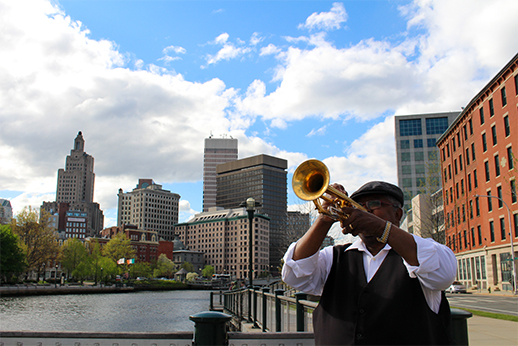 Ritchee Price playing the trumpet by the Providence River.